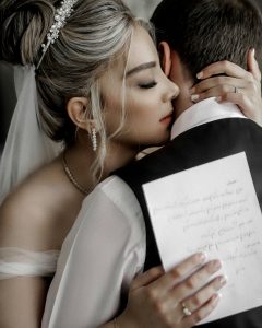 Bride hugging a groom, holding her vows in her hand